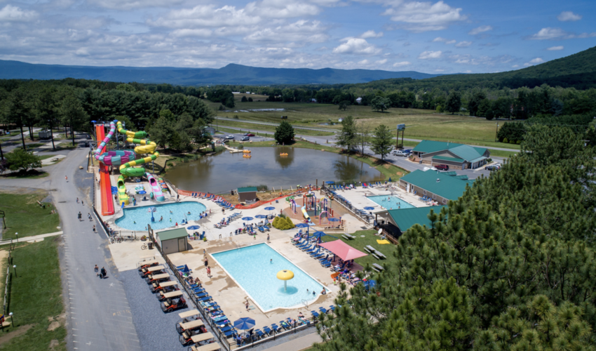  Aerial view of a campground with a waterpark, featuring pools, waterslides and a lake.