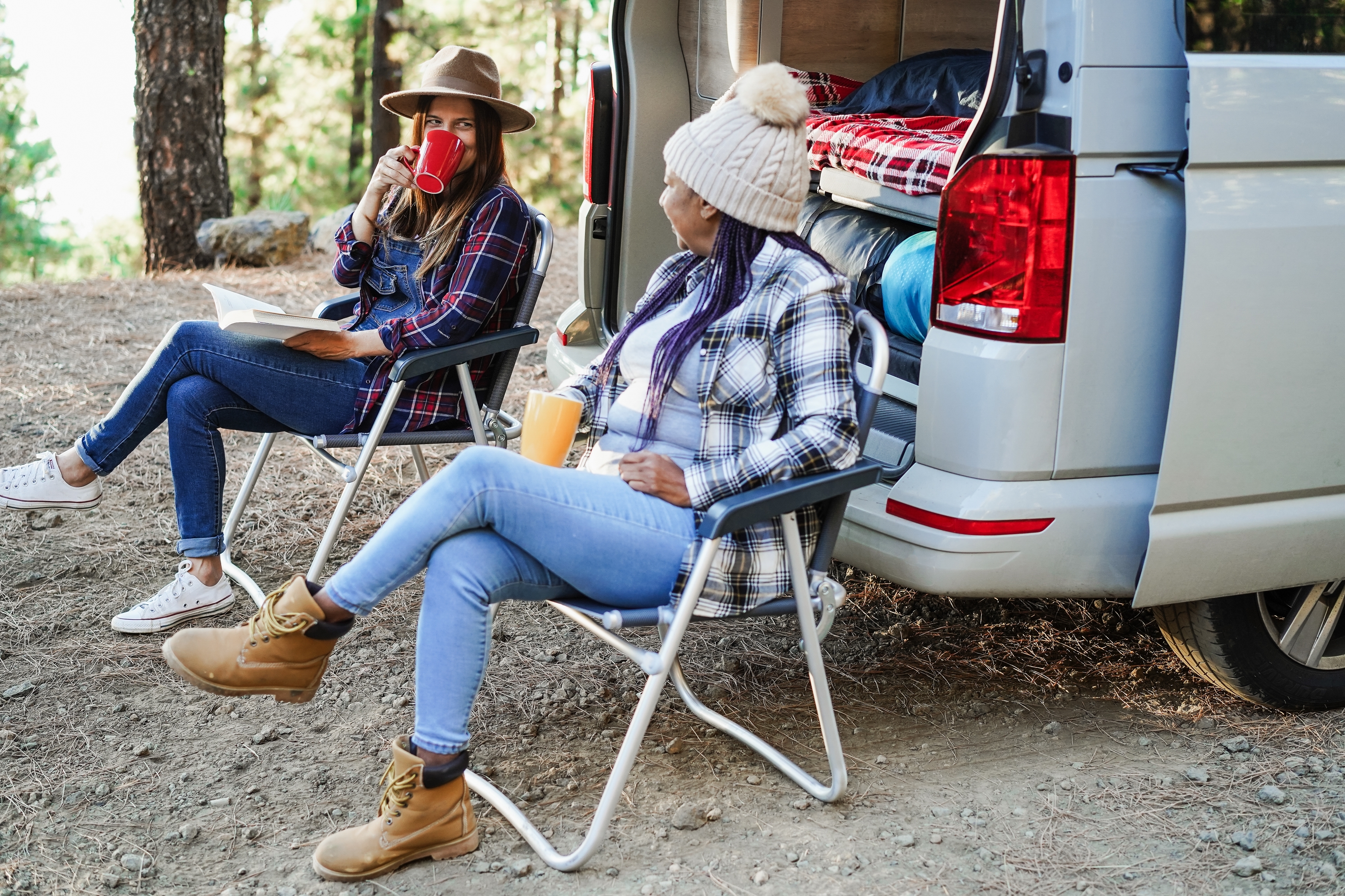 Two women enjoying coffee outside of a Class B RV