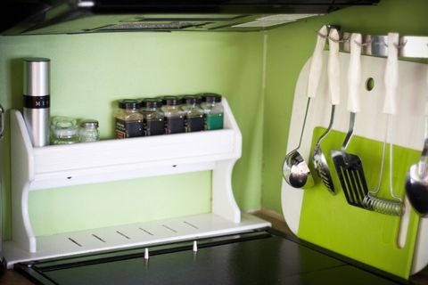 The corner of an RV kitchen with a storage rack for items like spices on one side; the other side shows kitchen utensils hanging out of the way to free up counter space